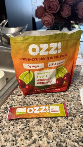 Reviewer's opened Cherry Limeade bag of Ozzi crave-crushing drink sticks with a single stick laid out on the kitchen counter.