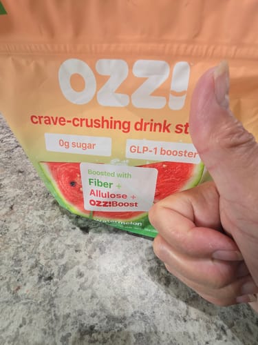 Customer gives a thumbs-up next to the Ozzi crave-crushing drink mix packaging on a counter.