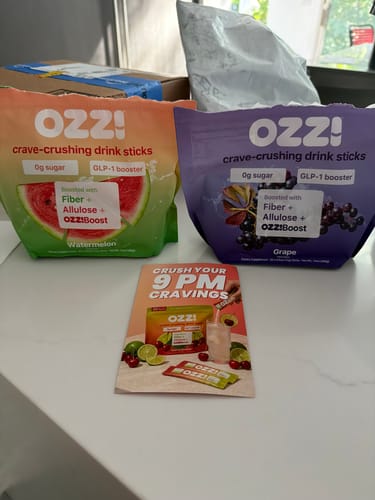 Customer's two pouches of Ozzi crave-crushing drink sticks, in Watermelon and Grape flavors, on a counter.