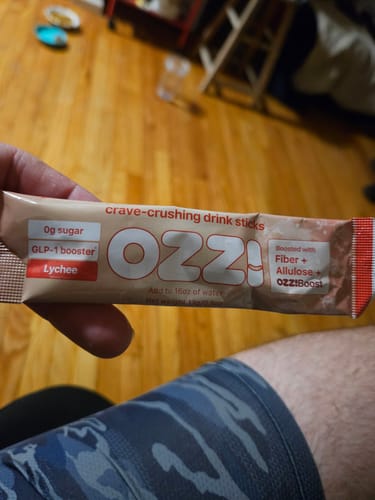 Reviewer holds up a Lychee-flavor Ozzi crave-crushing drink stick.
