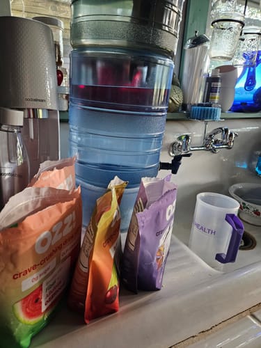 Customer's three colorful bags of Ozzi Crave Crusher lined up in a kitchen sink.