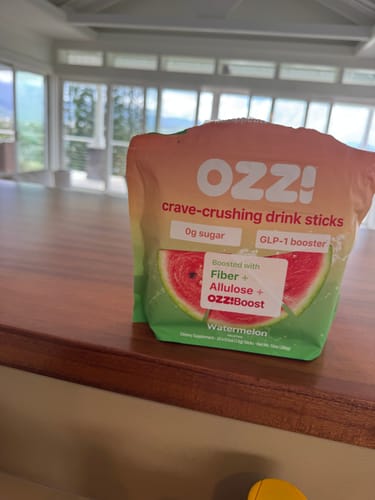 Reviewer's watermelon-flavored pouch of Ozzi crave-crushing drink sticks sitting on a wooden surface.