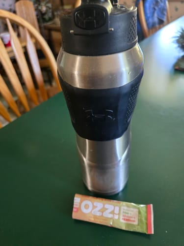 Customer's packet of Ozzi, The Crave Crusher v2, resting on a table beside a shaker bottle.
