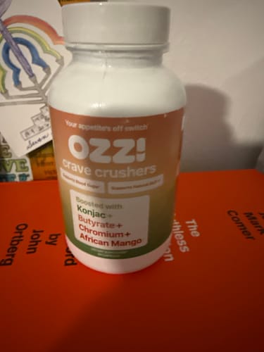Reviewer's bottle of Ozzi Crave Crushers capsules on a stack of books.