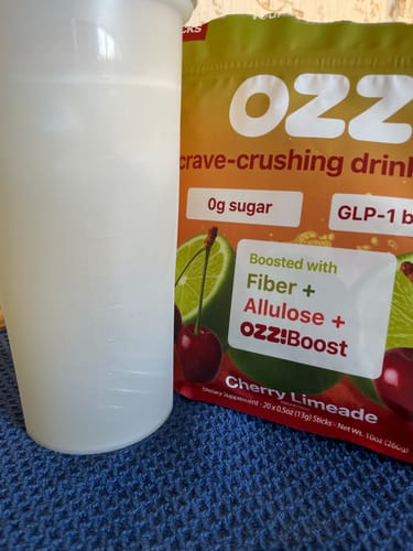Reviewer's Ozzi Crave Crusher pouch in Cherry Limeade flavor next to a cup.