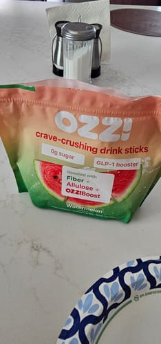 Customer's Watermelon bag of Ozzi drink sticks on a white kitchen island.