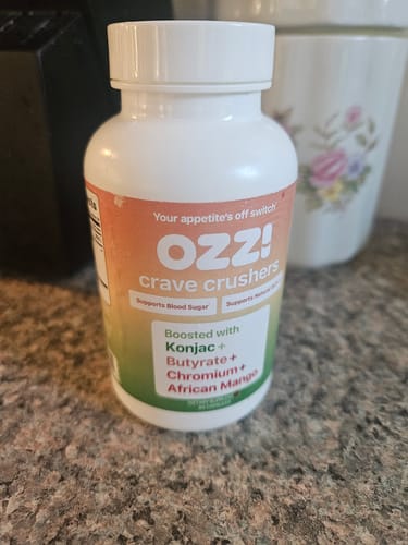 Customer's bottle of Ozzi Crave Crushers capsules on a granite kitchen counter.