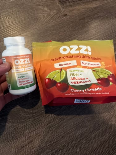 Customer holds their Ozzi Crave Crushers capsule bottle next to a Cherry Limeade bag of the drink sticks.